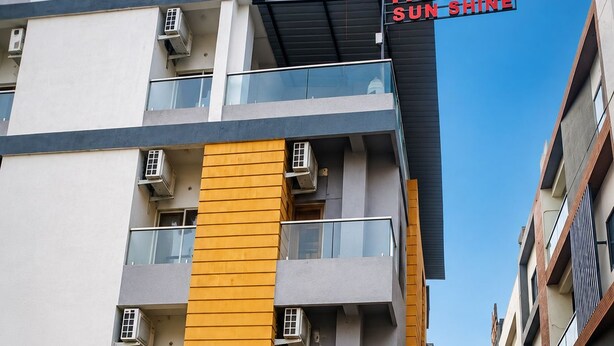 Un moderno edificio di un hotel con un cartello che indica 'HOTEL SUN SHINE – Camere con e senza aria condizionata'.