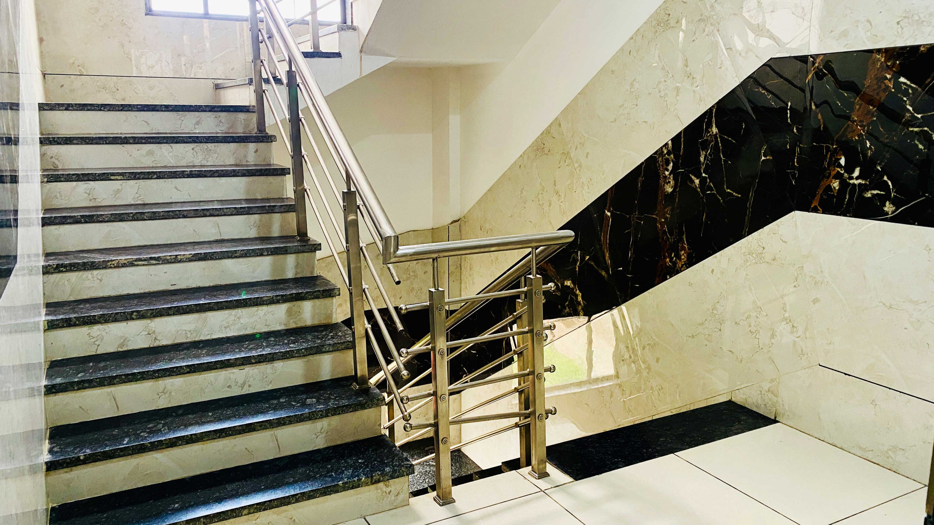 Una escalera con barandillas de metal y peldaños de mármol.