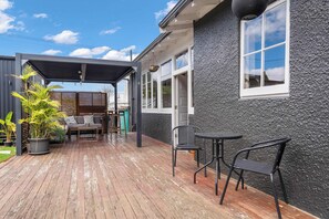 Eine überdachte Terrasse mit Holzdeck, einem Sitzbereich mit Tisch und Stühlen sowie einem Blumentopf.