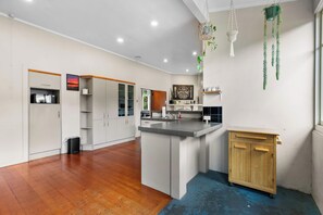 A modern kitchen with white cabinetry, a granite countertop, and a wooden cabinet. - Spacious 3 Bedroom Villa in Central Whangarei (Whangārei)