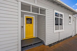 Ein Haus mit gelber Haustür, einer kleinen Veranda und einem Fenster.