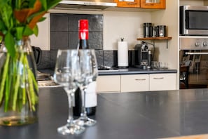 Eine Küche mit einer Weinflasche, Gläsern und einer Kaffeemaschine auf der Arbeitsplatte.