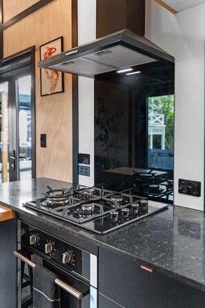 Eine moderne Küche mit Gasherd, Backofen und einer Edelstahl-Dunstabzugshaube.
