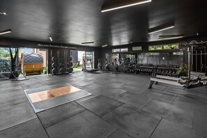Ein Fitnessstudio mit Krafttrainingsgeräten, Laufbändern und einer Trainingsbank.