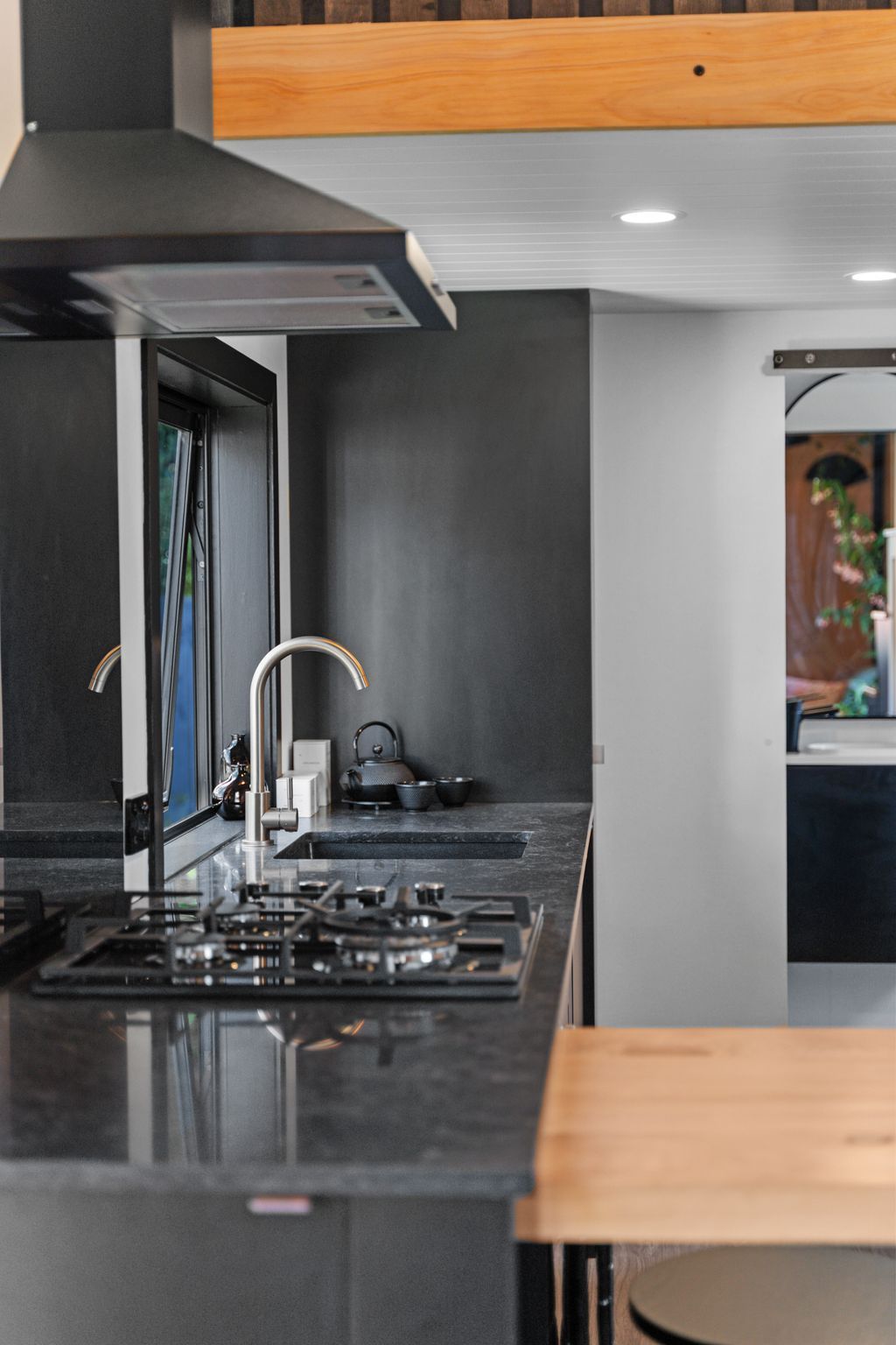 A modern kitchen with a gas stove, stainless steel appliances, and a wooden ceiling.