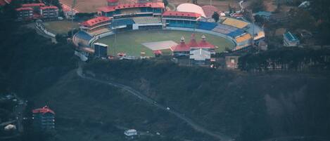 An aerial view of a stadium with a central field surrounded by seating areas and buildings.