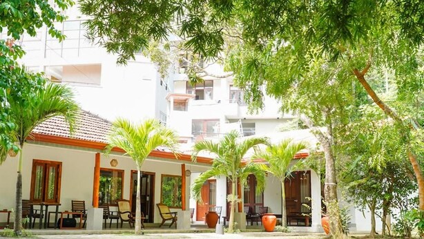 A building with multiple rooms, outdoor seating, and palm trees. - Hiri point villa (Dikwella)