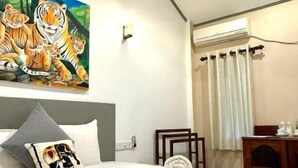 A hotel room with a bed, a painting of tigers, a ceiling fan, and a window with curtains. - Hiri point villa (Dikwella)