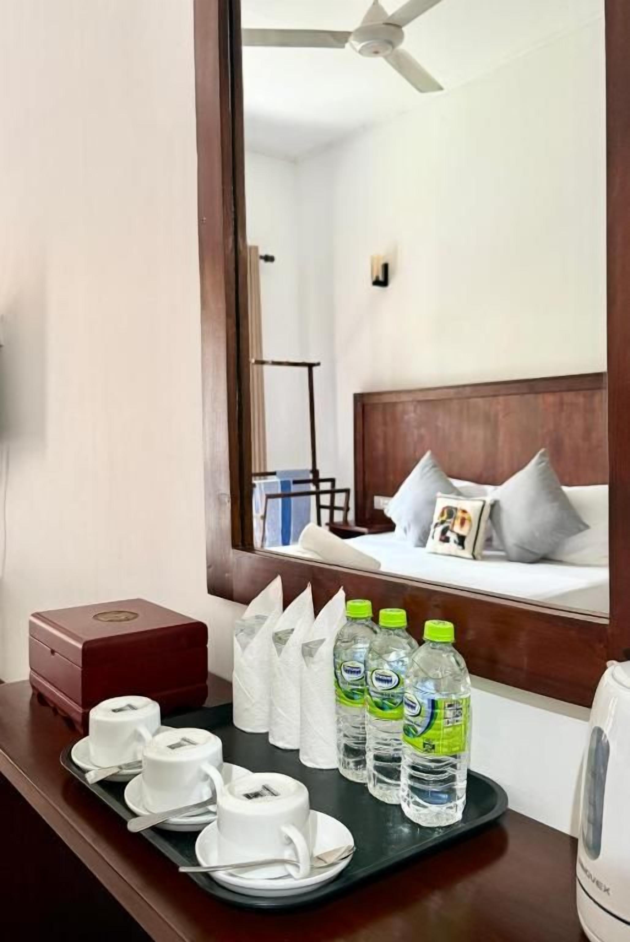 A hotel room with a bed, a tray with toiletries, and a mirror reflecting the room.