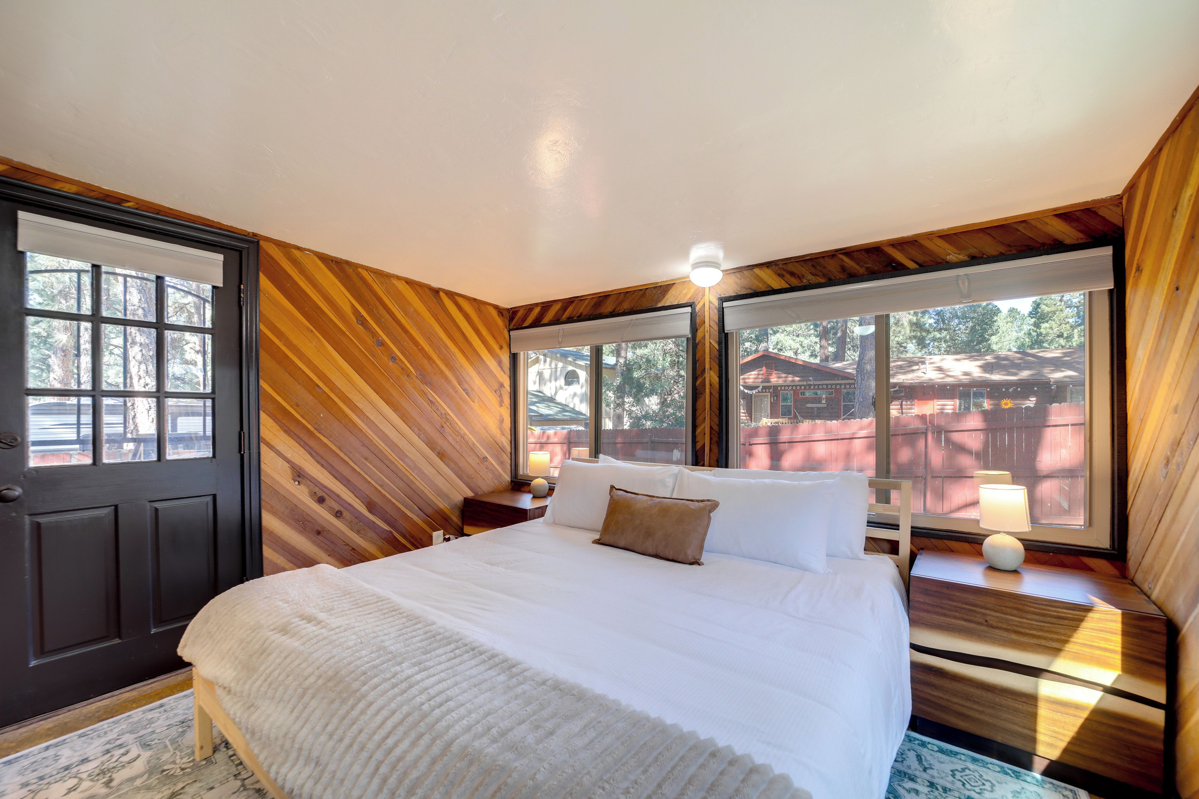 Une chambre avec un grand lit, des murs en bois et une vue sur l’extérieur.