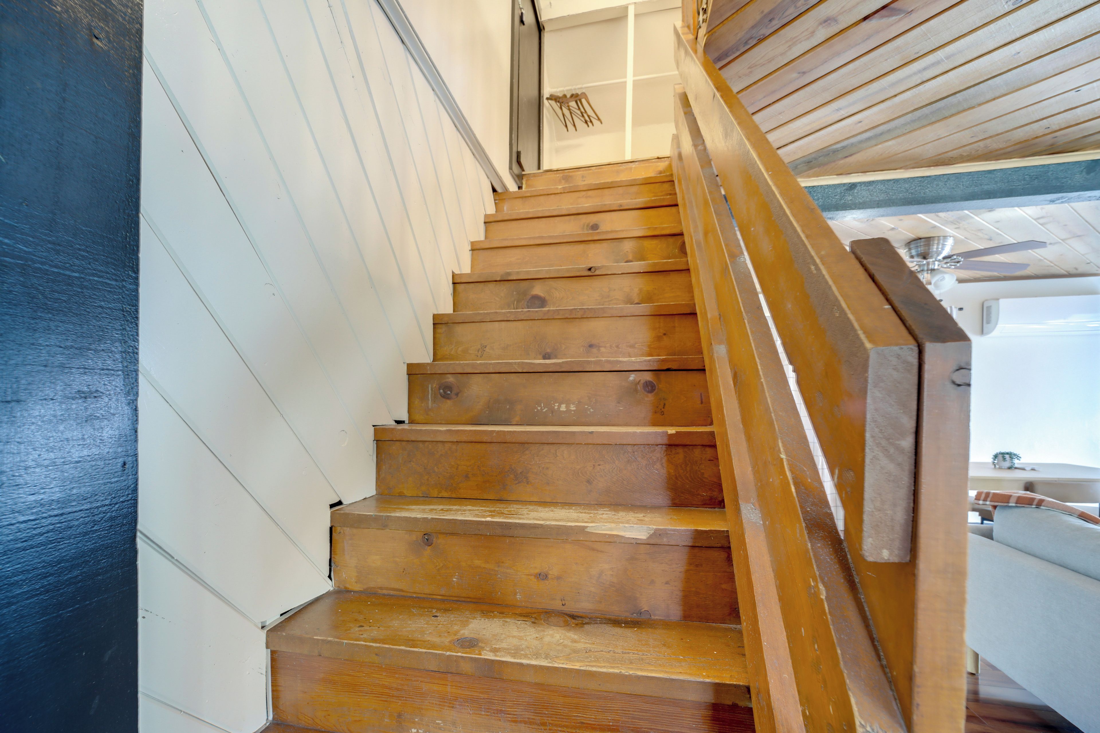 Eine Holztreppe mit Handlauf, der zu einer Zwischenplattform führt.