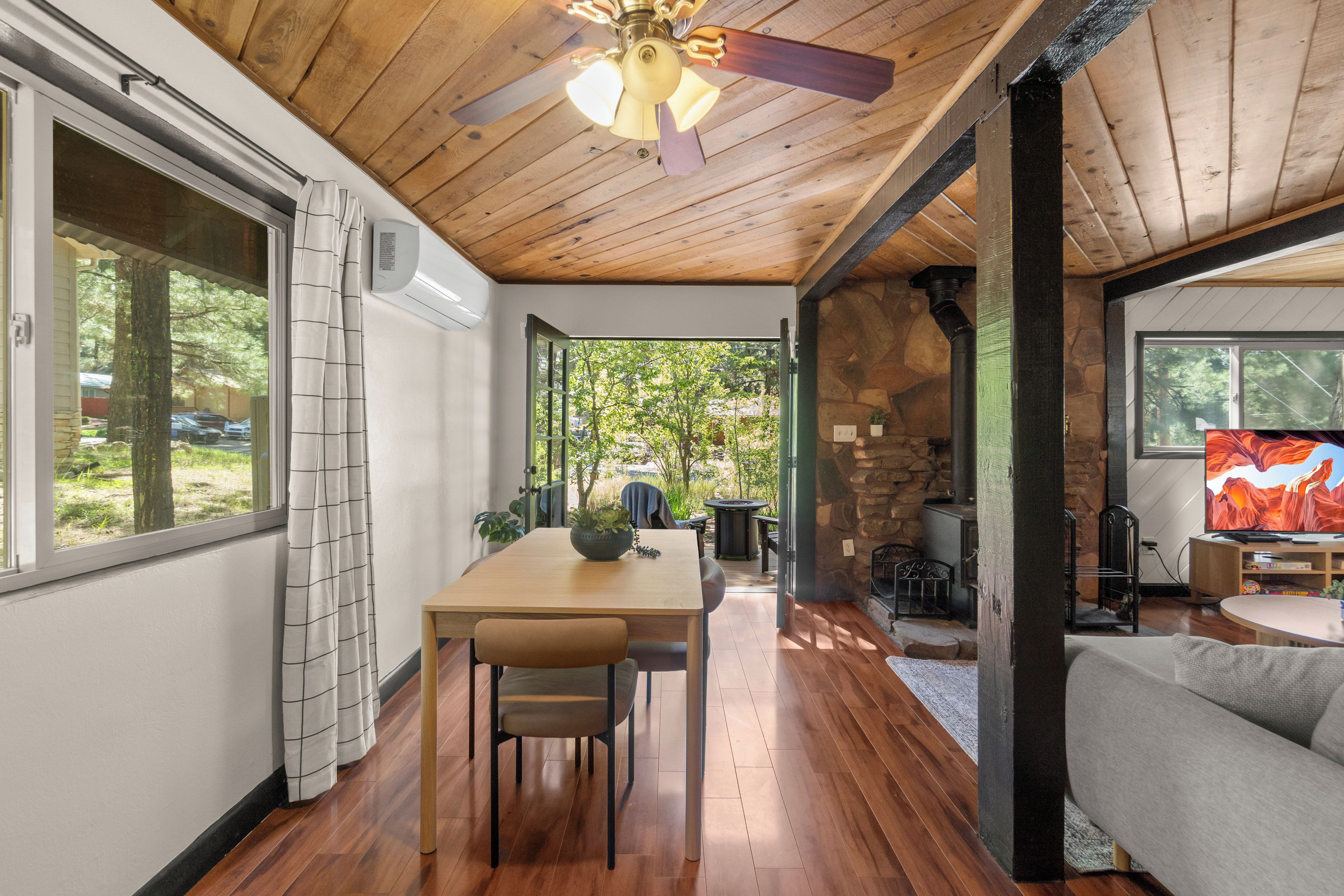 A cozy interior with a dining area, a stone fireplace, and a television.
