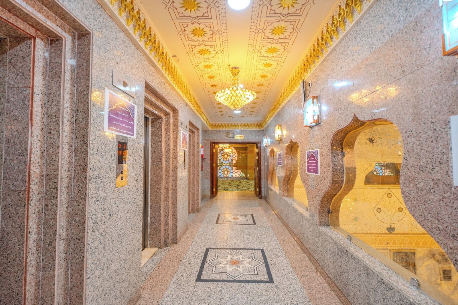 A hallway with a patterned floor, a chandelier, and wall decorations.