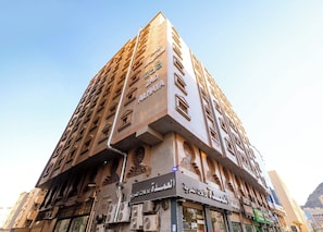 Un grand immeuble à étages, caractérisé par un mélange de styles architecturaux, notamment des fenêtres en arc et des éléments décoratifs.
