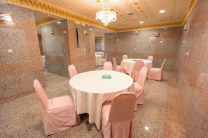 A conference room with round tables, chairs, and a chandelier. - Zad Al Hayat Hotel (Makkah)