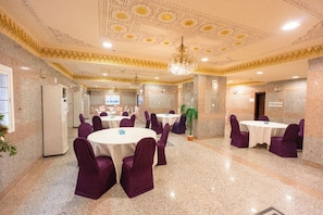 Une salle de conférence avec des tables rondes, des chaises violettes et un lustre.