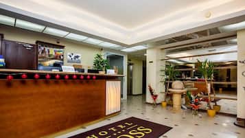 Et hotellets reception med en trædisk, et verdenskort på væggen og plantekasser.