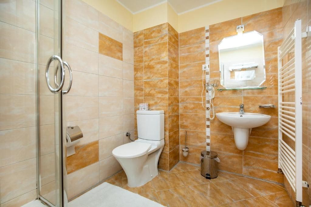 Un baño con cabina de ducha de vidrio, inodoro, lavamanos y toallero.