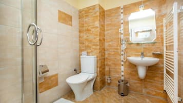 Un baño con cabina de ducha de vidrio, inodoro, lavamanos y toallero.