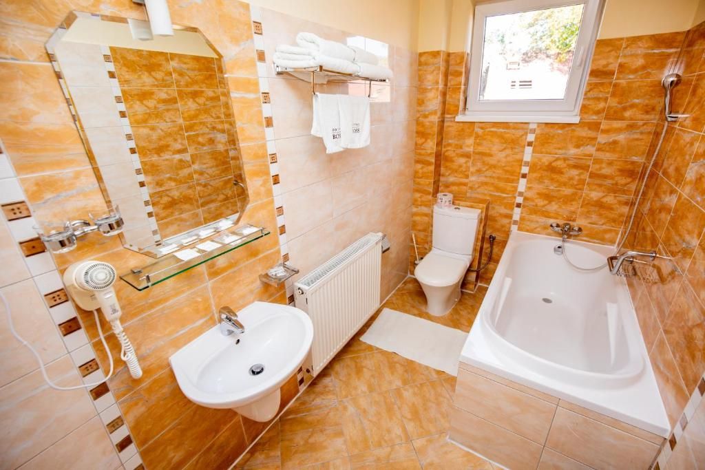A bathroom with a bathtub, a sink, a toilet, and a mirror.