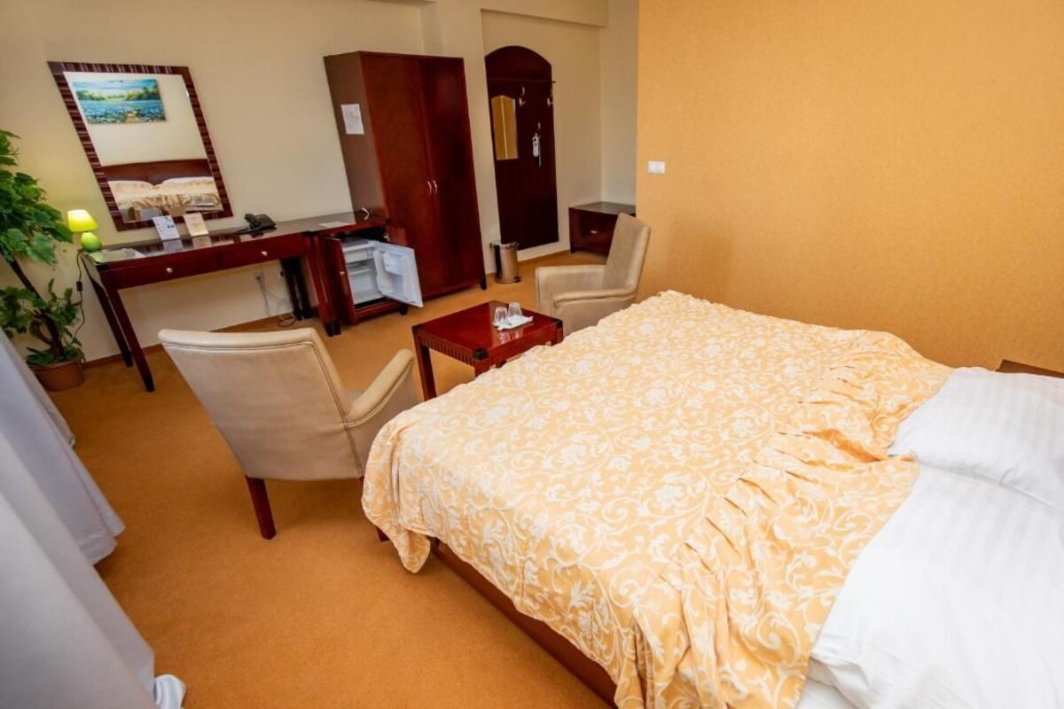 Una habitación de hotel con cama, escritorio, silla, una mesita y armario.