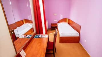 Una habitación de hotel con dos camas, un escritorio de madera, un espejo y una cortina roja.