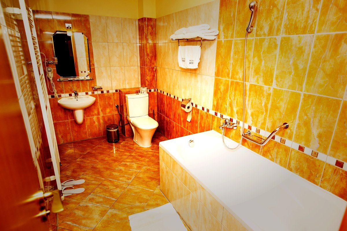 A bathroom with a bathtub, toilet, sink, and a mirror.