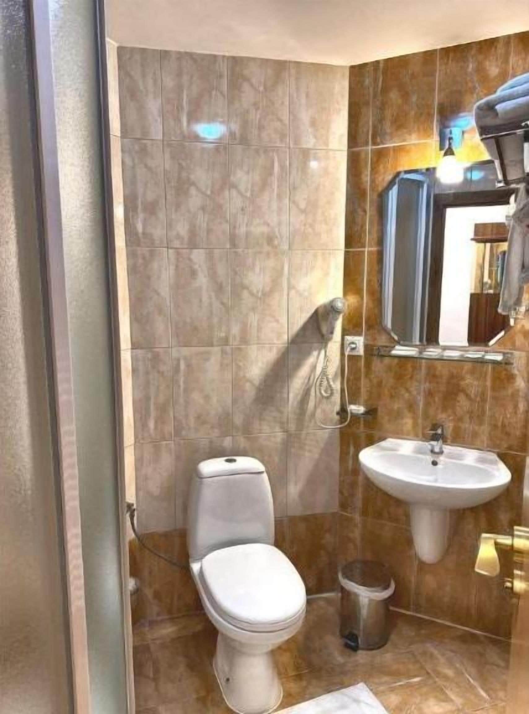 Un baño con inodoro, lavamanos y zona de ducha.