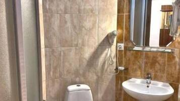 Un baño con inodoro, lavamanos y zona de ducha.