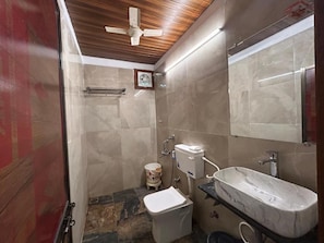 Un bagno con un lavabo in marmo, un water, una doccia e una ventola a soffitto.