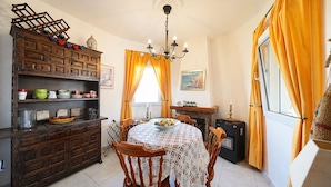 Zona pranzo con tavolo rotondo, sedie, lampadario e camino.
