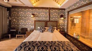 Ein Hotelzimmer mit einem großen Bett, einem Holzkopfende, einem Schreibtisch und einem Fenster mit Blick.