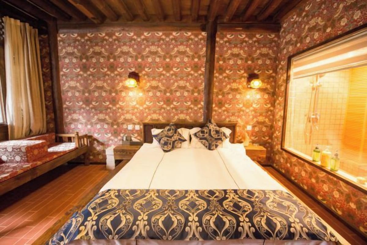 Una habitación de hotel con una cama grande, dos lámparas fijadas a la pared y una ventana con vistas.