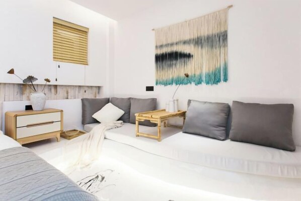 Una sala de estar moderna con un sofá blanco, una mesita de madera y un tapiz colgado en la pared.