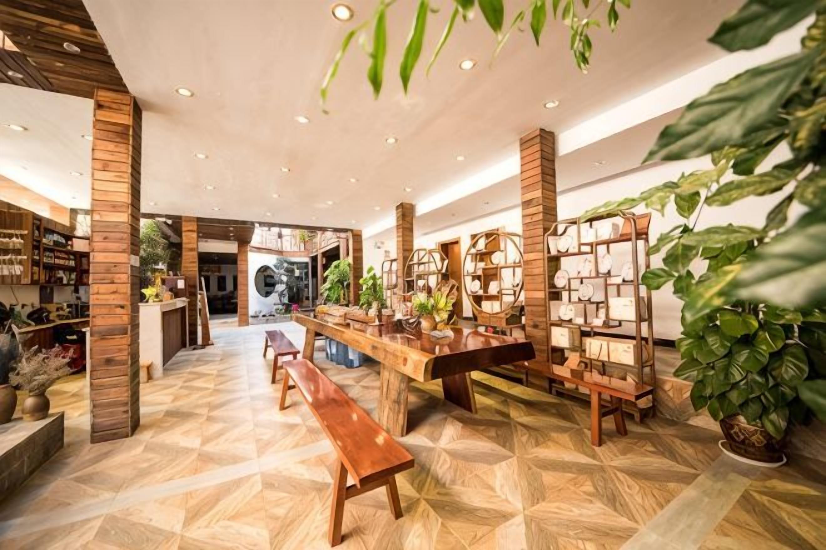 A spacious indoor area with wooden benches, a long table, and a wall with a grid of bookshelves.