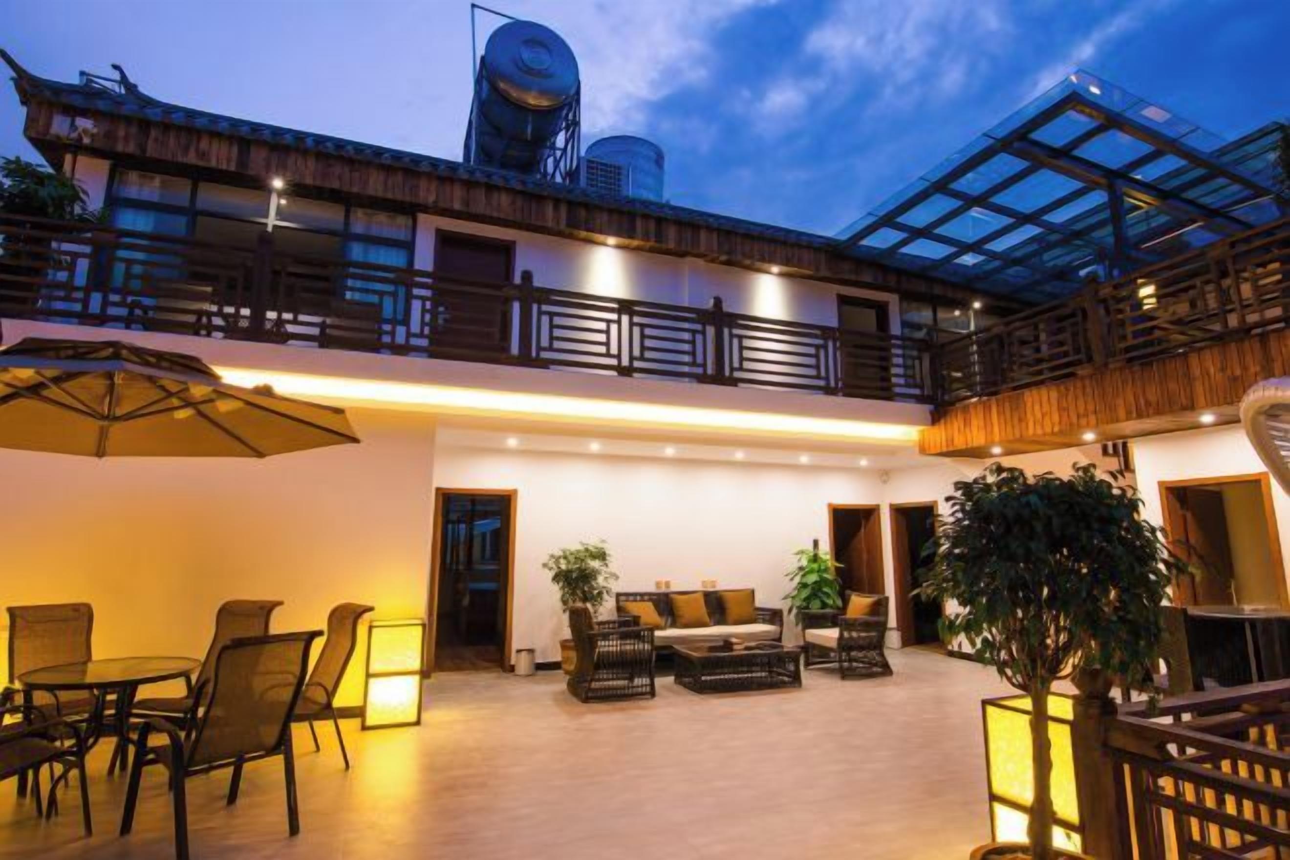 A modern building with a glass balcony, outdoor seating area, and a water tank on the roof.