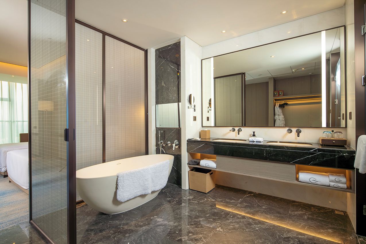 A modern bathroom with a freestanding bathtub, a large mirror, and a vanity with a countertop.