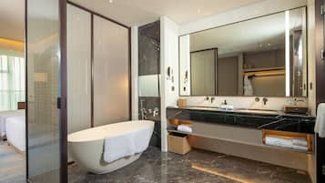 A modern bathroom with a freestanding bathtub, a large mirror, and a vanity with a countertop.