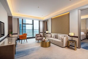 Et moderne hotelværelse med et stort vindue, en sofa, et sofabord, et skrivebord og en seng.