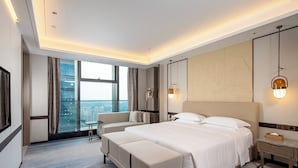 Quarto de hotel moderno com cama grande, área de estar e vista para a cidade.
