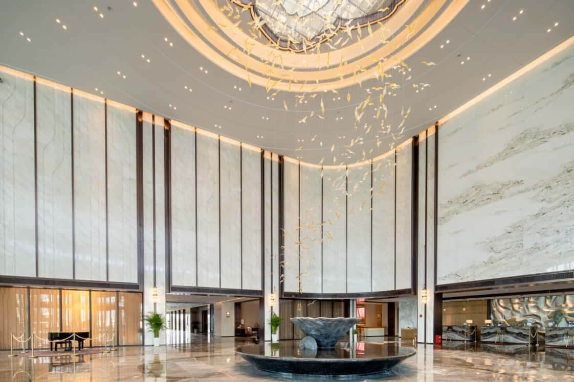 Een ruime lobby met een centrale fontein, hoge plafonds en een modern design.