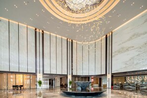 A spacious lobby with a central fountain, high ceilings, and a modern design.