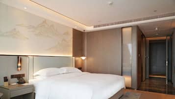 A hotel room with a bed, nightstand, wall-mounted lamp, and a large painting.