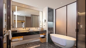 Uma casa de banho moderna com um espelho grande, uma banheira e uma cómoda com lavatório.