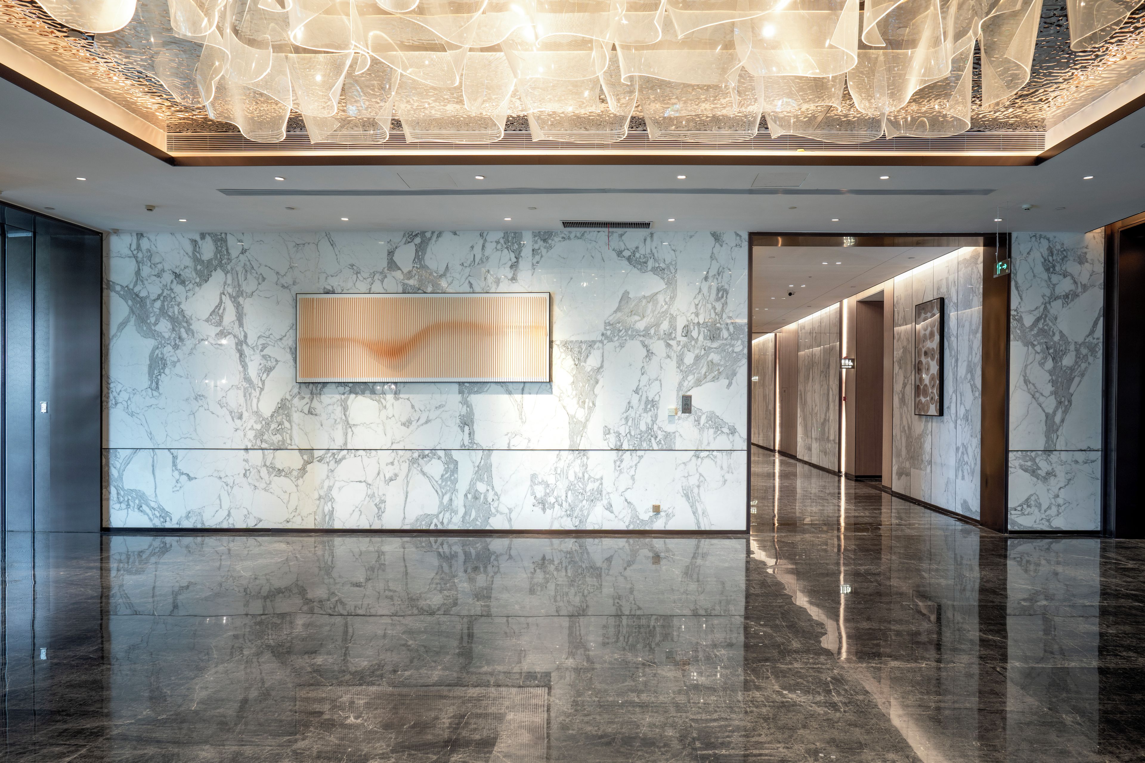 Een moderne lobby met marmeren wanden, een spiegelende vloer en een eigentijdse lamp.