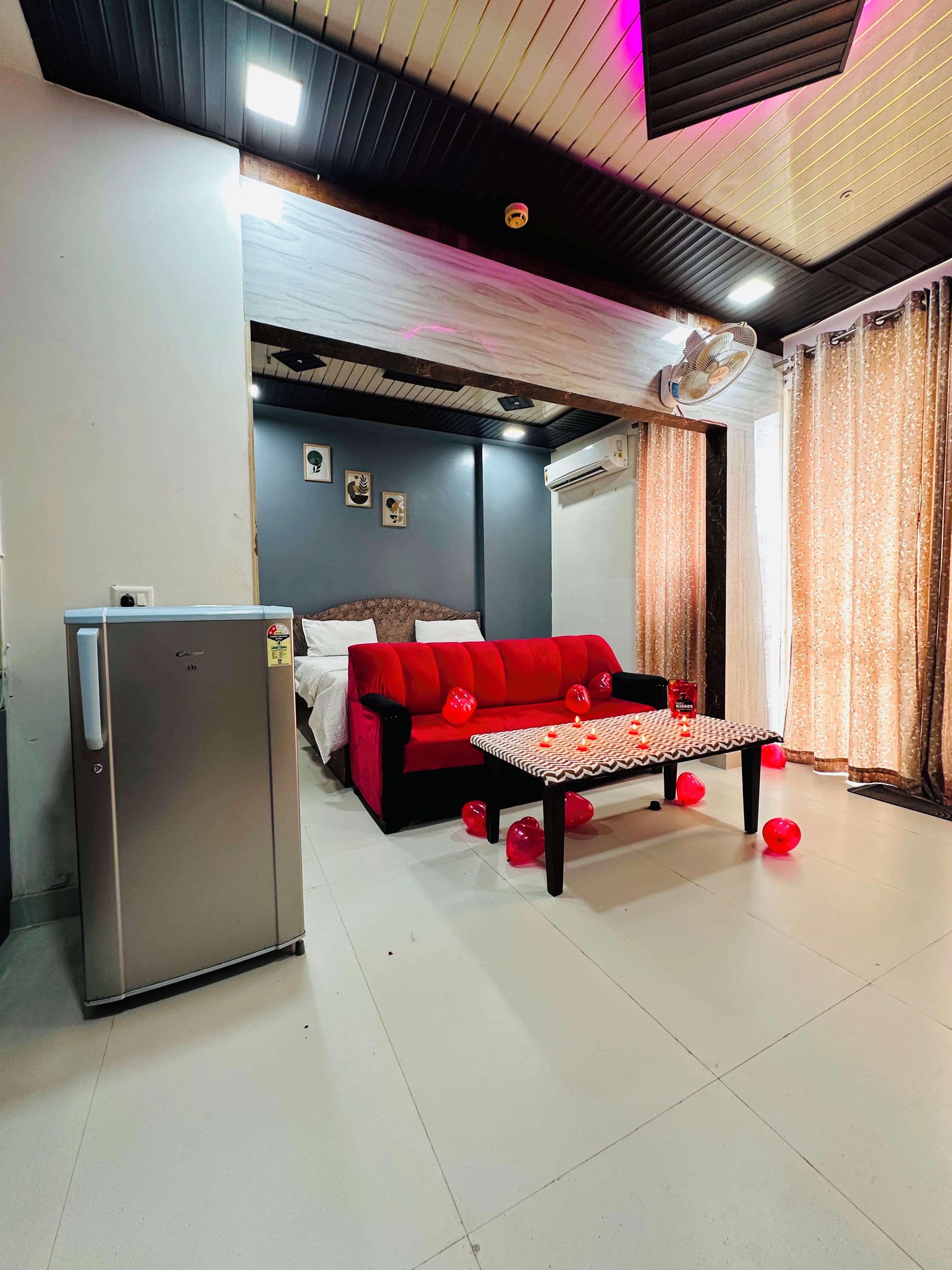 A compact living space with a sofa, a small table, and a refrigerator.