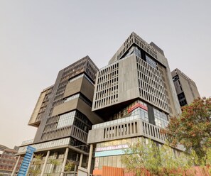 A multi-story building with a modern architectural design, featuring a mix of glass and concrete facades, and a prominent signage for a gym. - Classic Hotel Rajyash Rise (Ahmedabad)