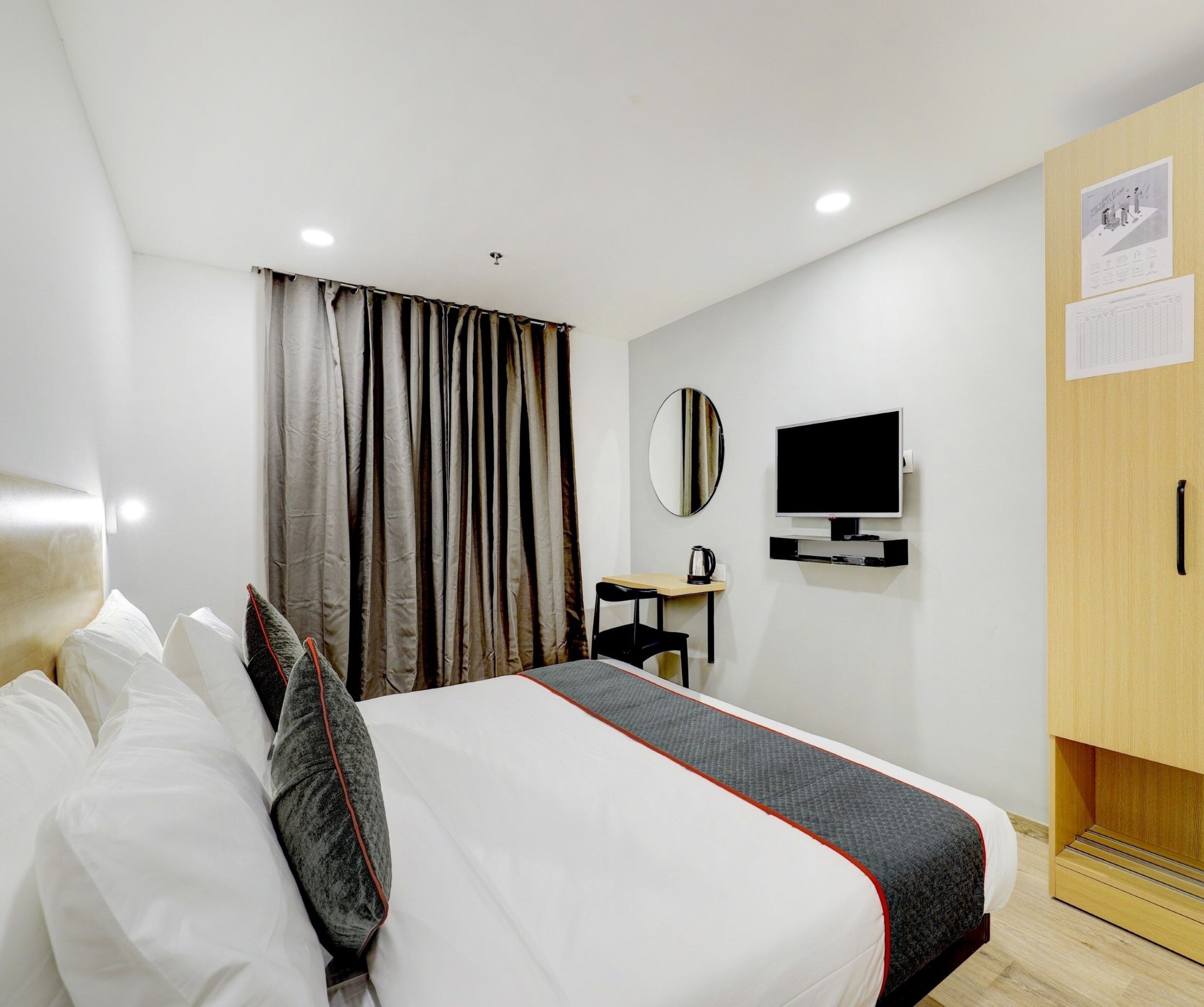 Een hotelkamer met een bed, een bureau, een televisie en een kledingkast.