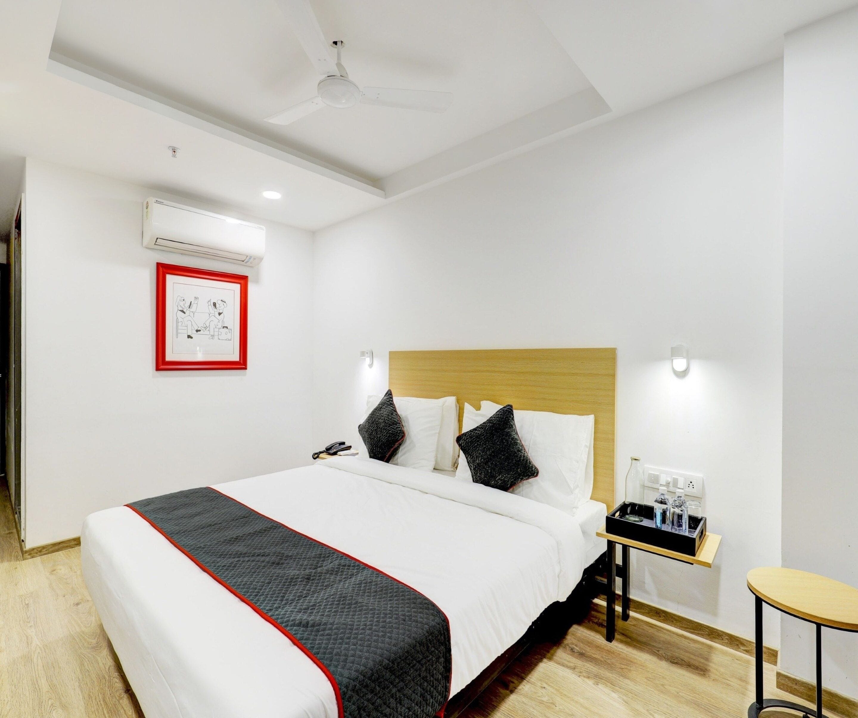 Een hotelkamer met een bed, nachtkastje en een klein tafeltje met een dienblad.