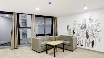 Ein modernes Zimmer mit einer Couch, einem kleinen Tisch und einer Wandmalerei, die eine Gruppe von Menschen zeigt.
